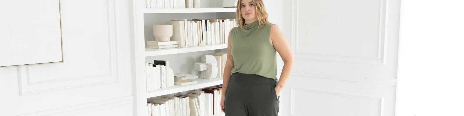 Black t-shirt folded on top of a beige, grey t-shirt with a silver pearl necklace over