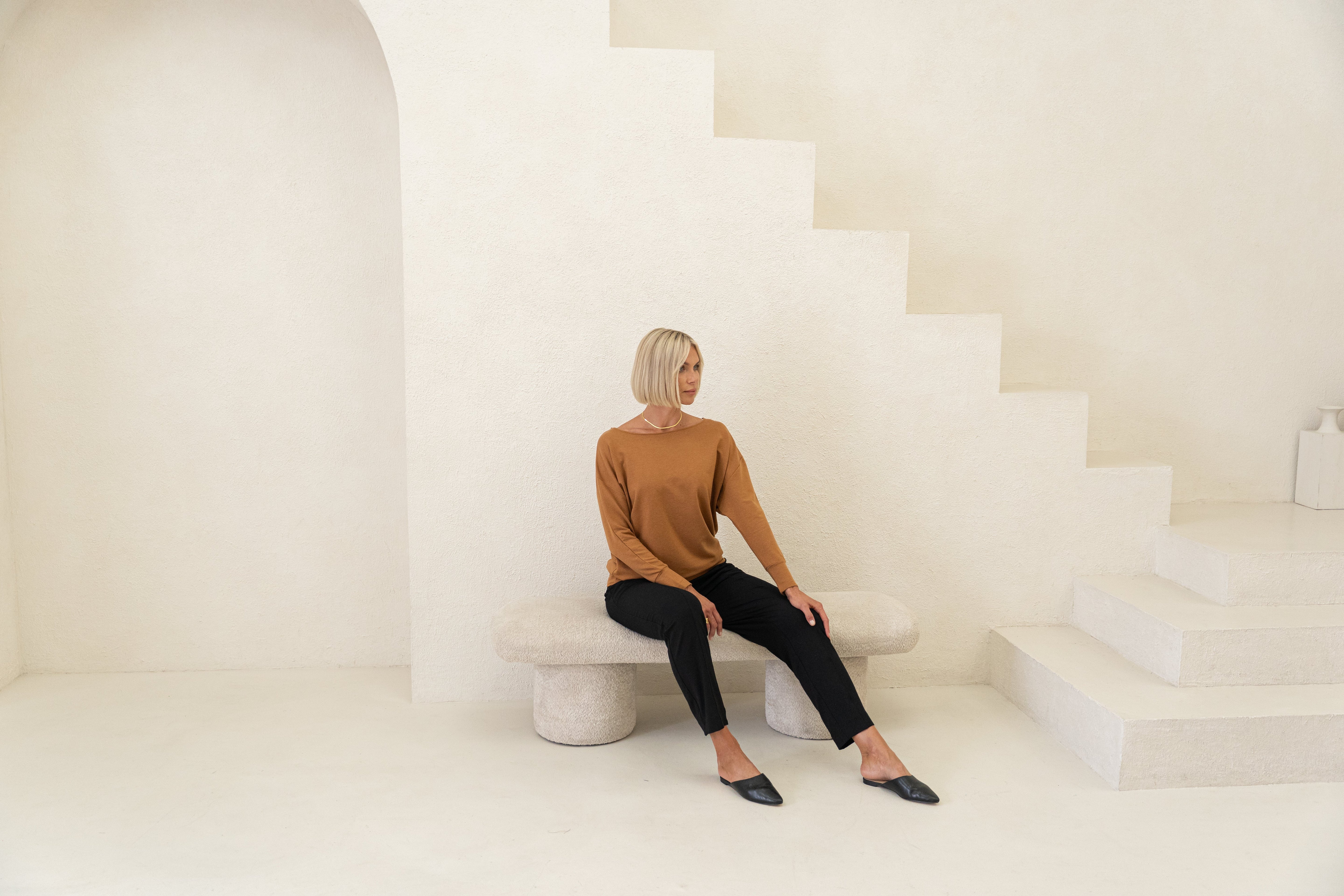 Black t-shirt folded on top of a beige, grey t-shirt with a silver pearl necklace over