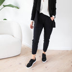 woman wearing a white button-up t-shirt with black sweatpants and black cardigan with black sneakers