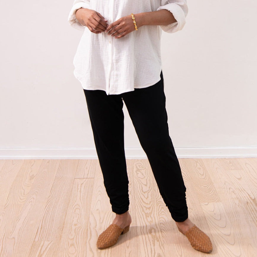 woman wearing black sweatpants with a white button-up shirt and brown mules