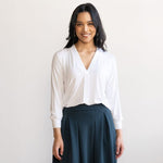 Woman wearing a loose flowing white v-neckline shirt with navy skirt