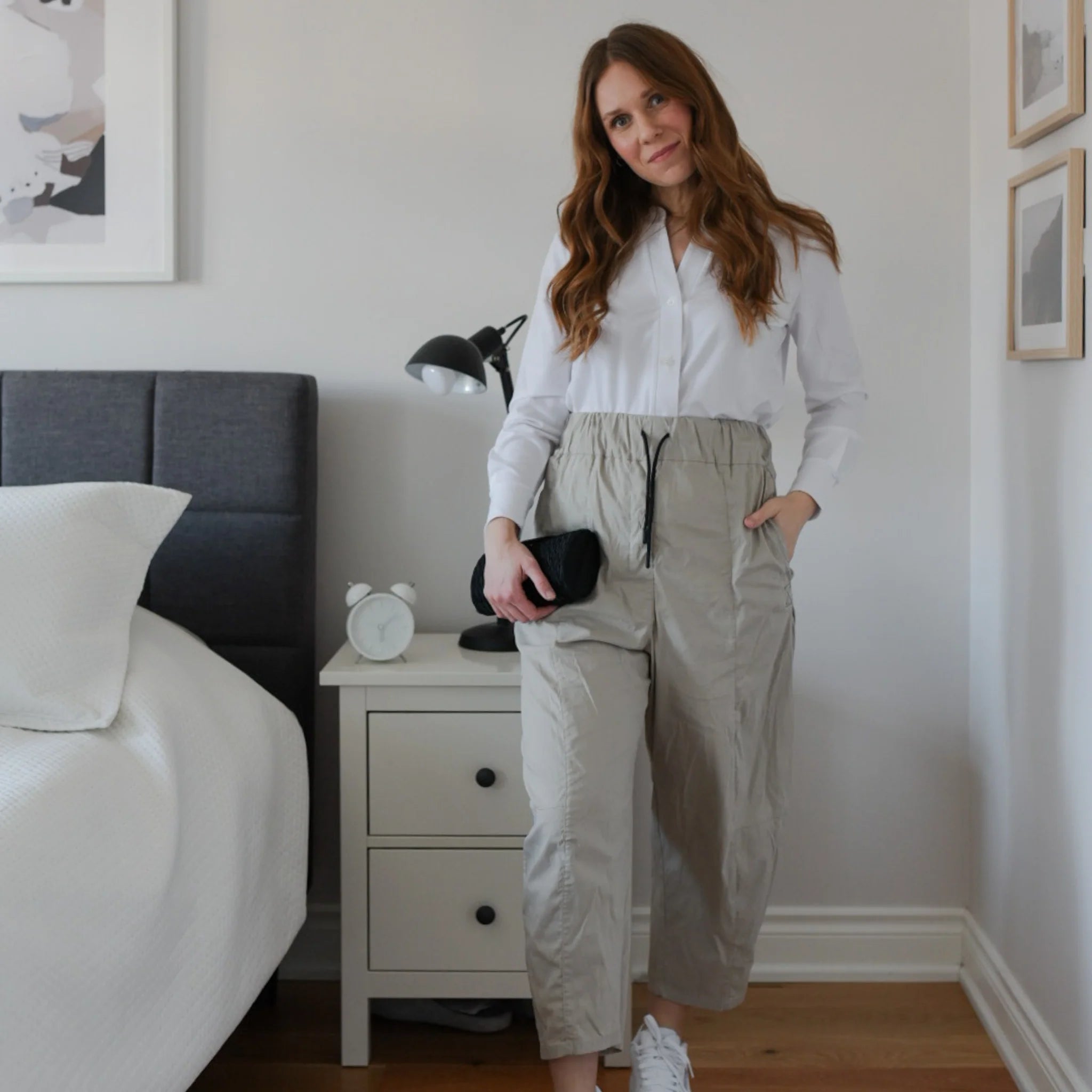 Woman wearing white long sleeve button up shirt with loose beige track pants