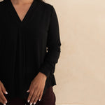 Woman wearing a loose flowing black v-neckline shirt 