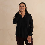 Woman wearing a loose flowing black v-neckline shirt 