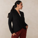 Woman wearing long sleeve black cardigan twisted at the front with white v-neckline shirt and red relaxed pants