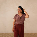 woman wearing a deep mauve cowl neck top with red high waisted pants