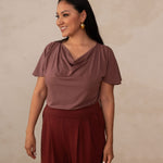 woman wearing a deep mauve cowl neck top with red high waisted pants