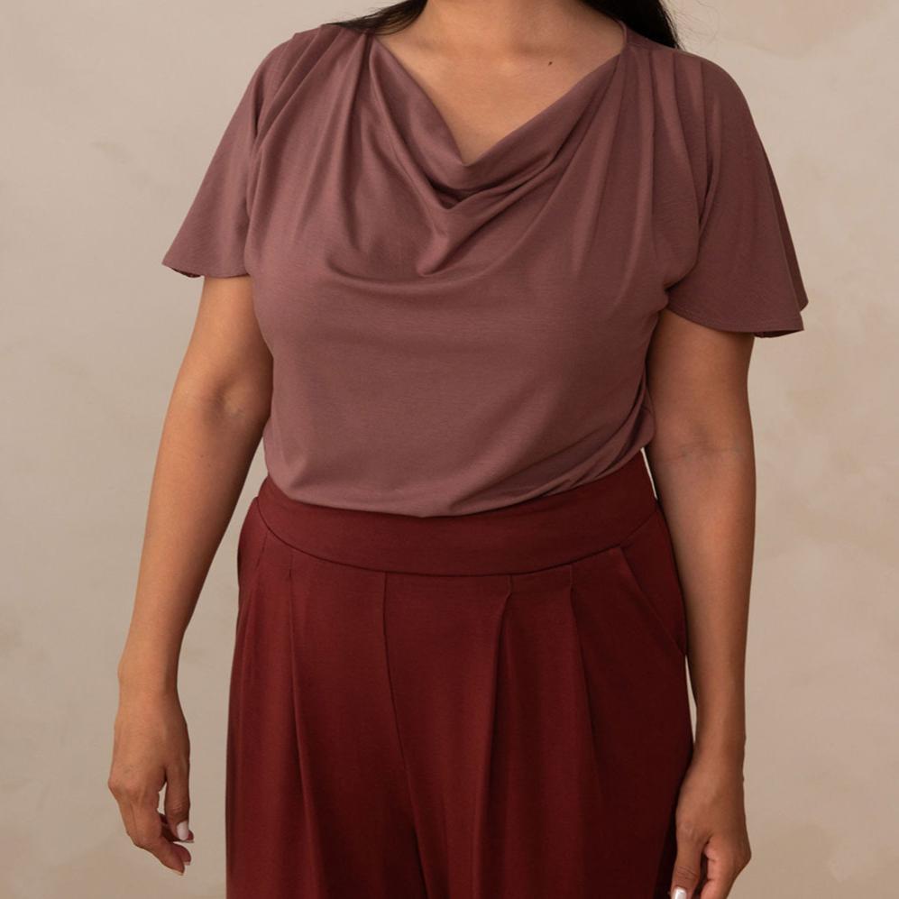 woman wearing a deep mauve cowl neck top with red high waisted pants