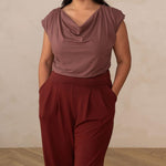 woman wearing a deep mauve cowl neck top with red high waisted pants