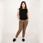 Woman wearing brown tailored stretchy ankle length pants with pockets paired with sleeveless black shirt