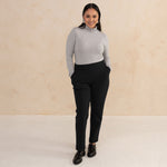 woman wearing a light grey turtleneck and tailored navy pants with black loafers
