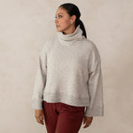 woman wearing a white relaxed high neck sweater and red pants