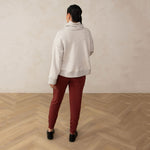 back of a woman wearing a white relaxed high neck sweater and red sweatpants with black loafers