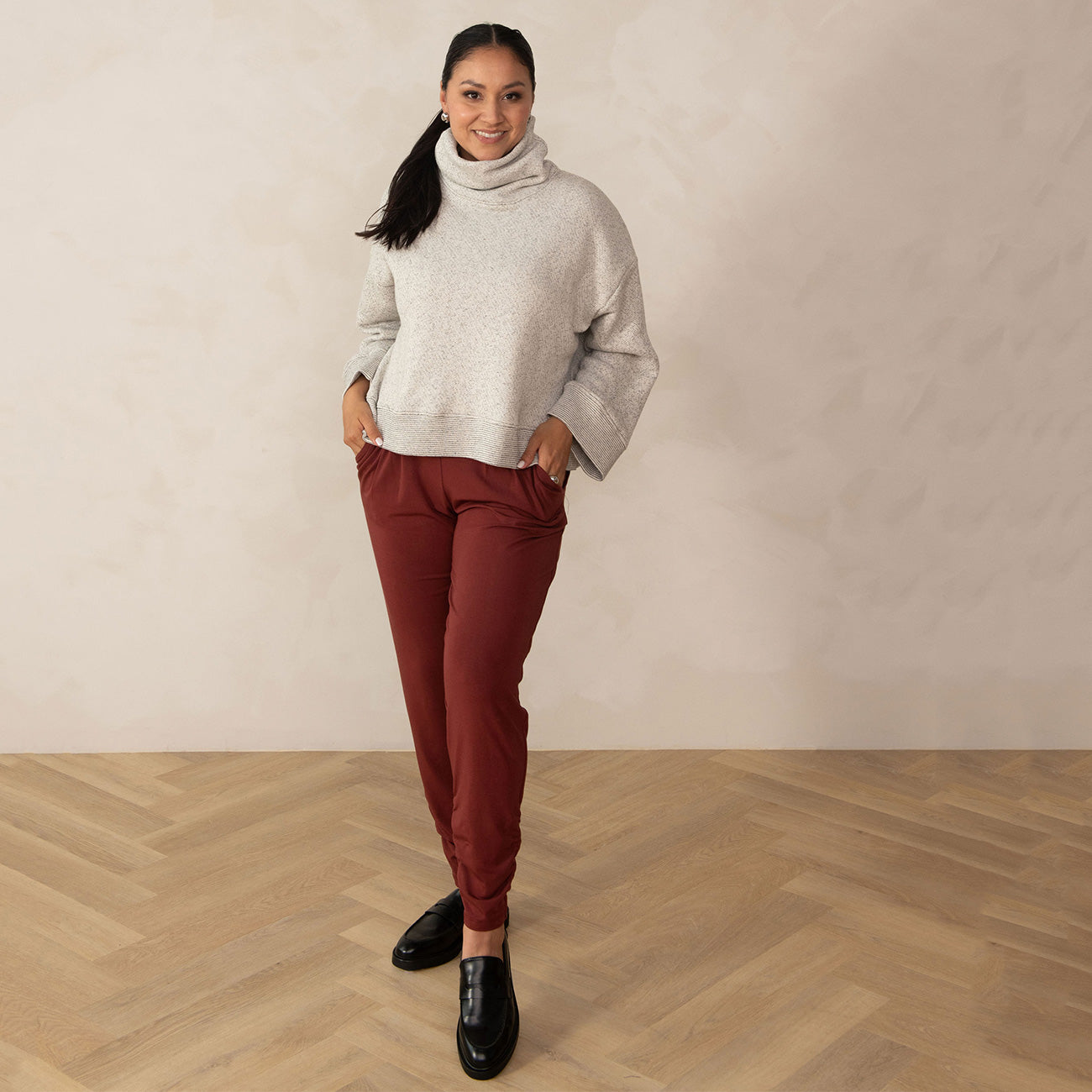 woman wearing a white relaxed high neck sweater and red sweatpants with black loafers
