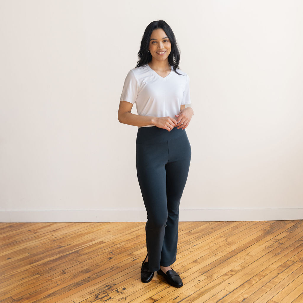 Woman wearing navy flare pants with a white v-neck t-shirt and black flat shoes