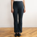 Woman wearing navy flare pants with a white v-neck t-shirt and black flat shoes