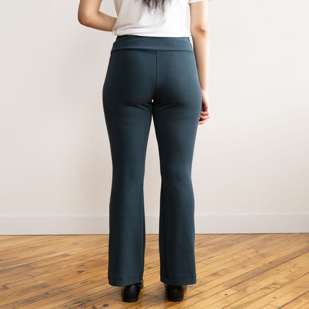 Woman wearing navy flare pants with a white v-neck t-shirt and black flat shoes