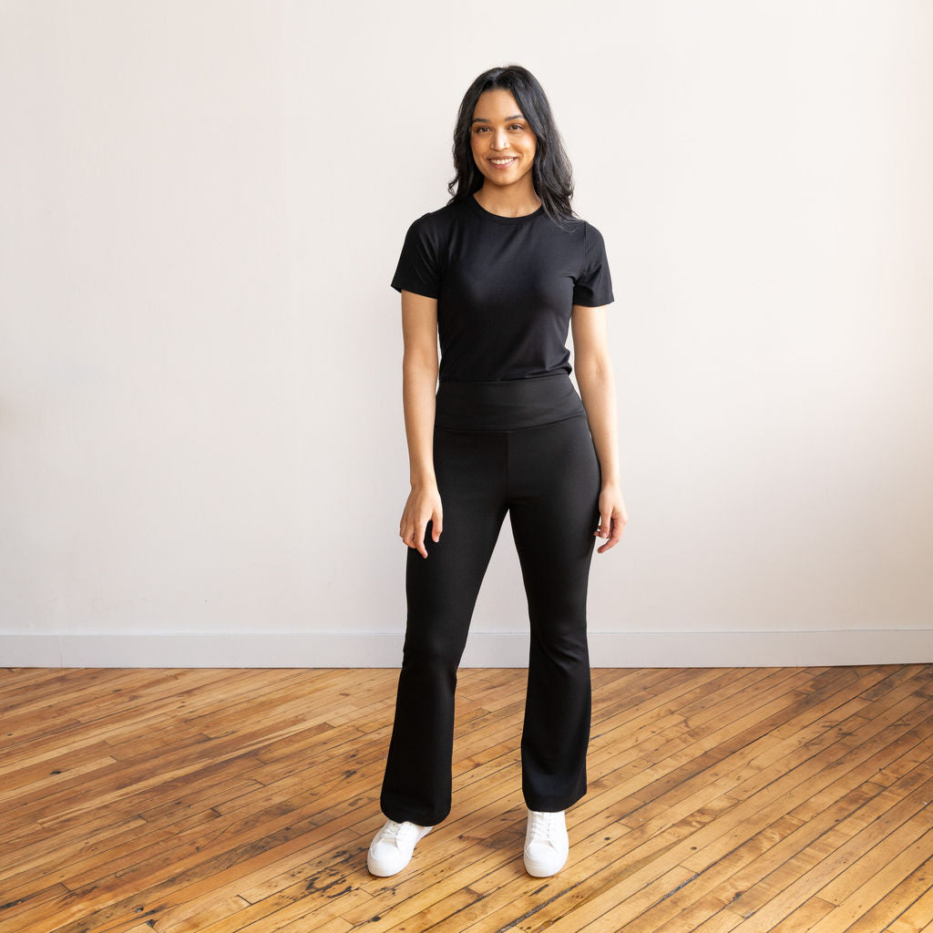 Woman wearing black flare pants with a black crewneck t-shirt and white sneakers