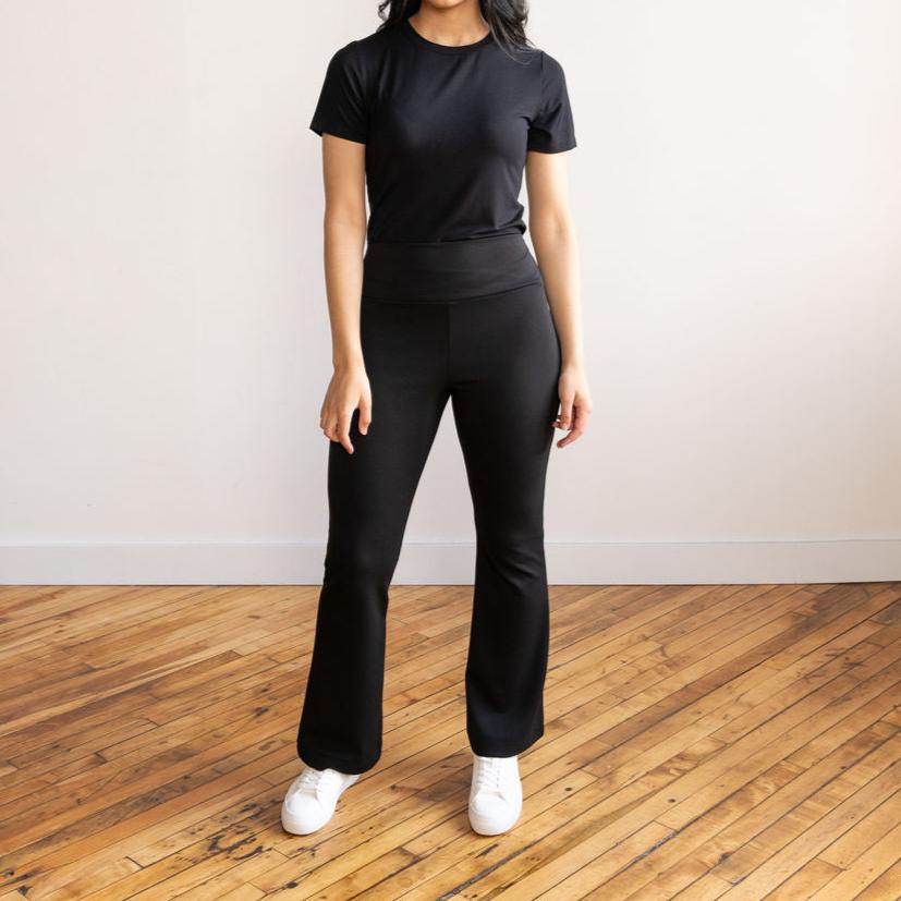 Woman wearing black flare pants with a black crewneck t-shirt and white sneakers