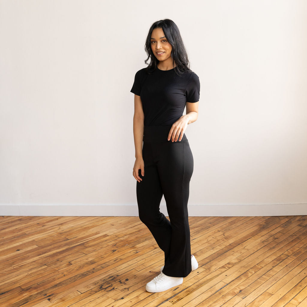 Woman wearing black flare pants with a black crewneck t-shirt and white sneakers