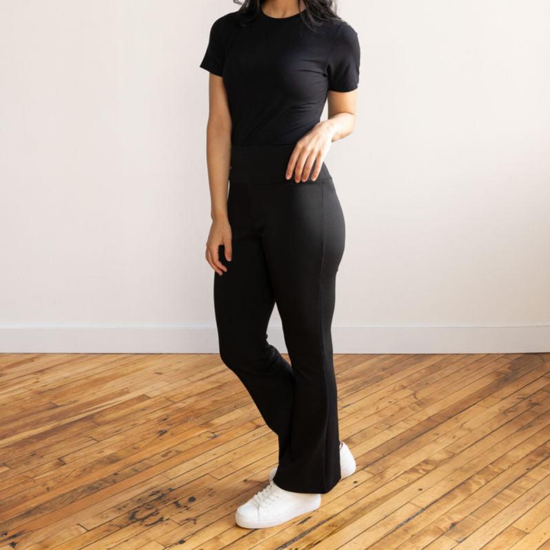 Woman wearing black flare pants with a black crewneck t-shirt and white sneakers