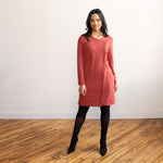 Woman wearing a brick colour long sleeve, knee length zipper dress with black tights