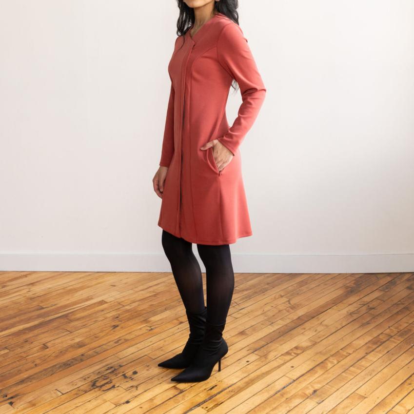 Woman wearing a brick colour long sleeve, knee length zipper dress with black tights