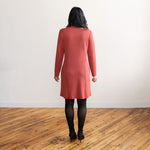Woman wearing a brick colour long sleeve, knee length zipper dress with black tights