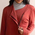 Detail of woman opening up a zipper of a brick colour jacket