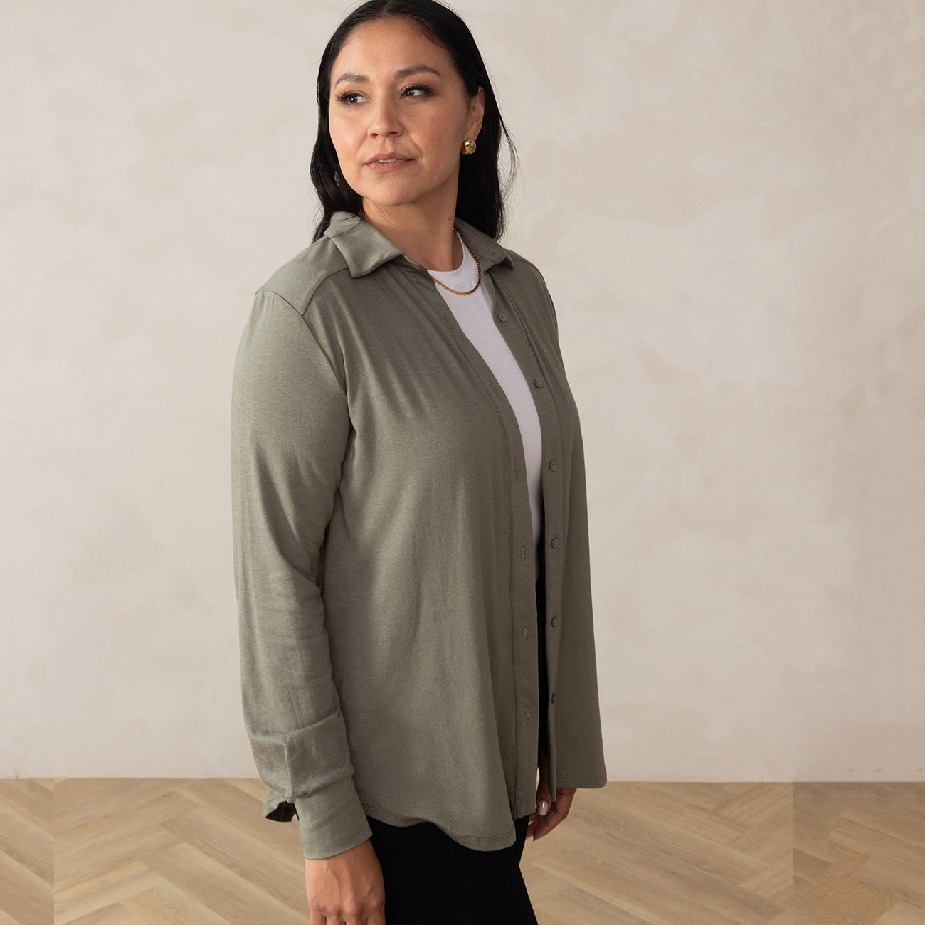 woman wearing a green button up on top of a white t-shirt with golden earrings