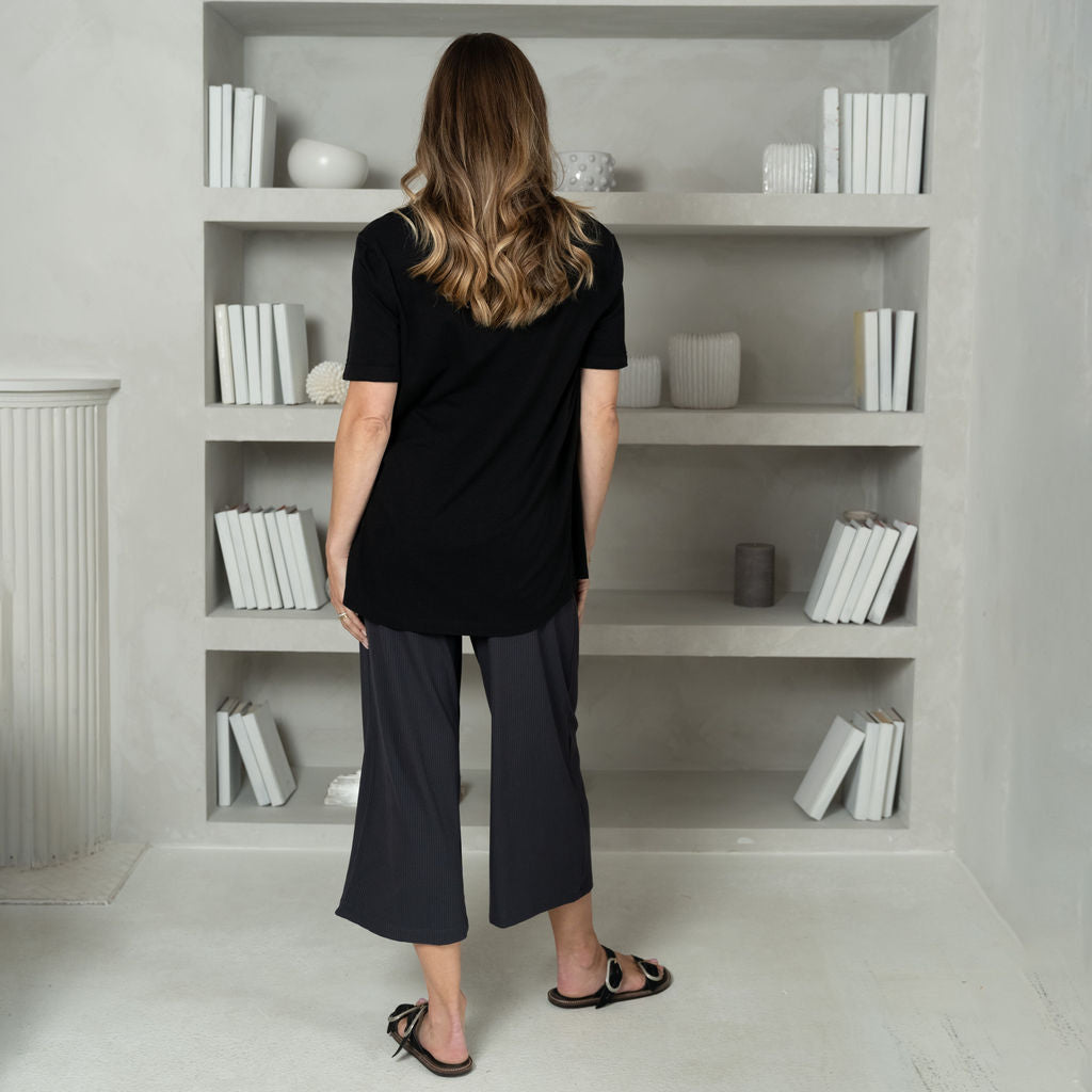 woman wearing a black v-neck t-shirt with a wide leg navy cropped pant