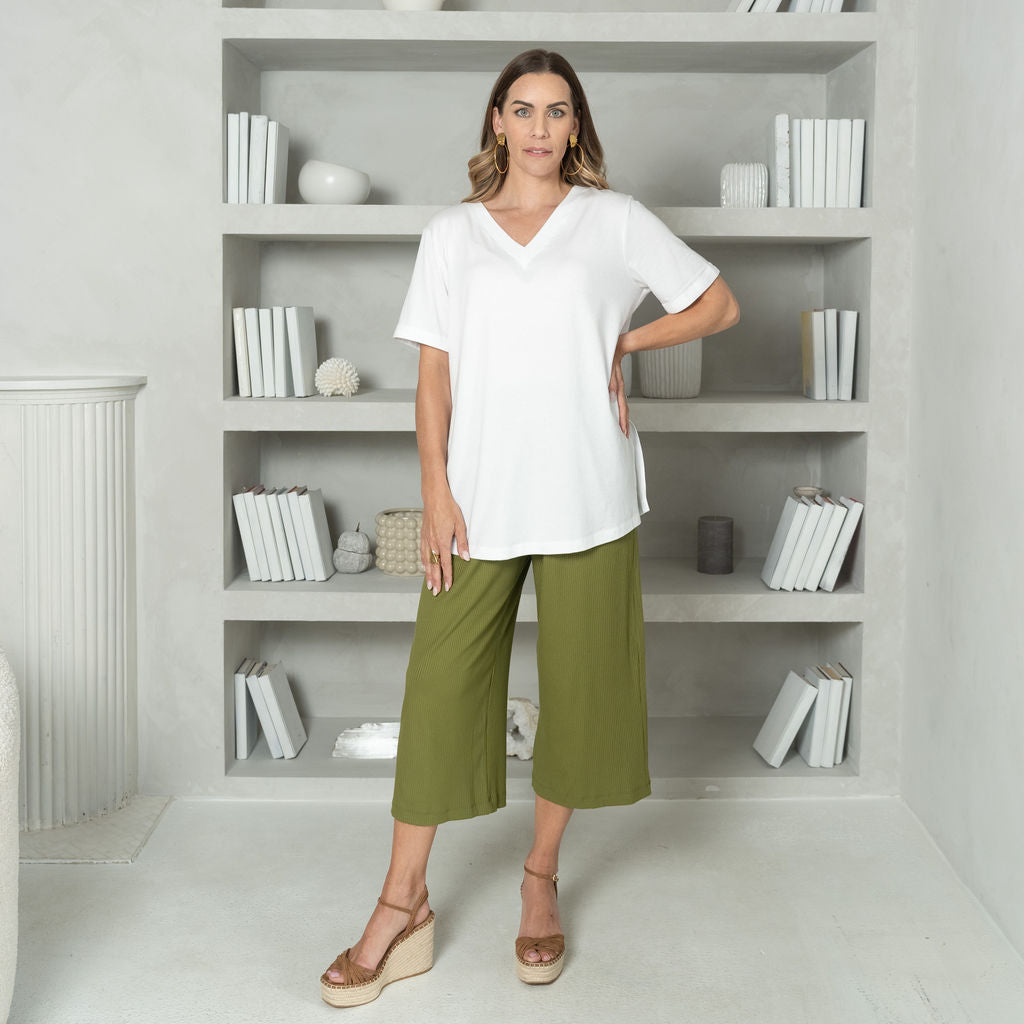 woman wearing a white v-neck t-shirt with a wide leg green cropped pant