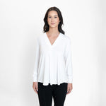 Woman wearing a loose flowing white v-neckline shirt with black leggings