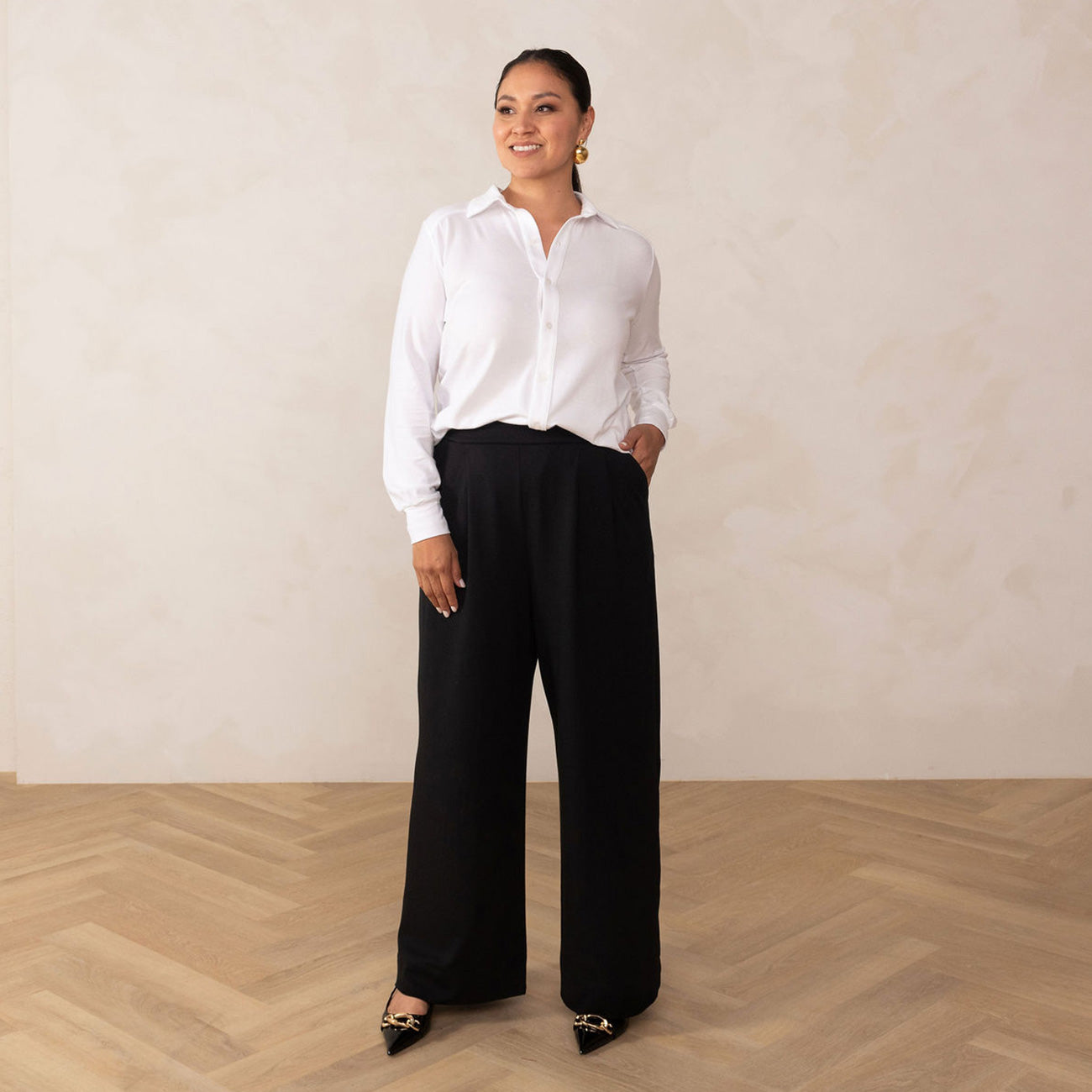 woman wearing a white button-up shirt paired with a black high waisted wide leg pant and black heels