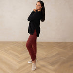 woman wearing a long sleeve scoop neck black top paired with red pants and beige sneakers