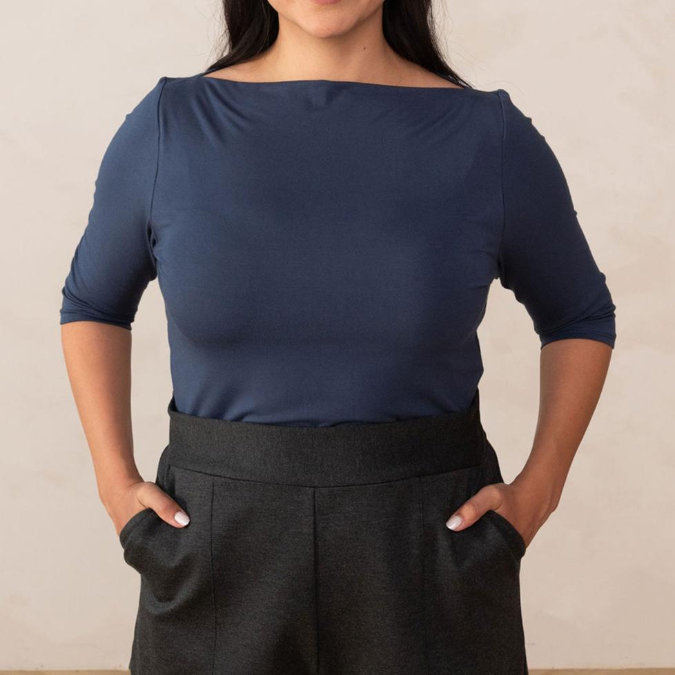 woman wearing a navy blue boat neck top and grey high waisted pants