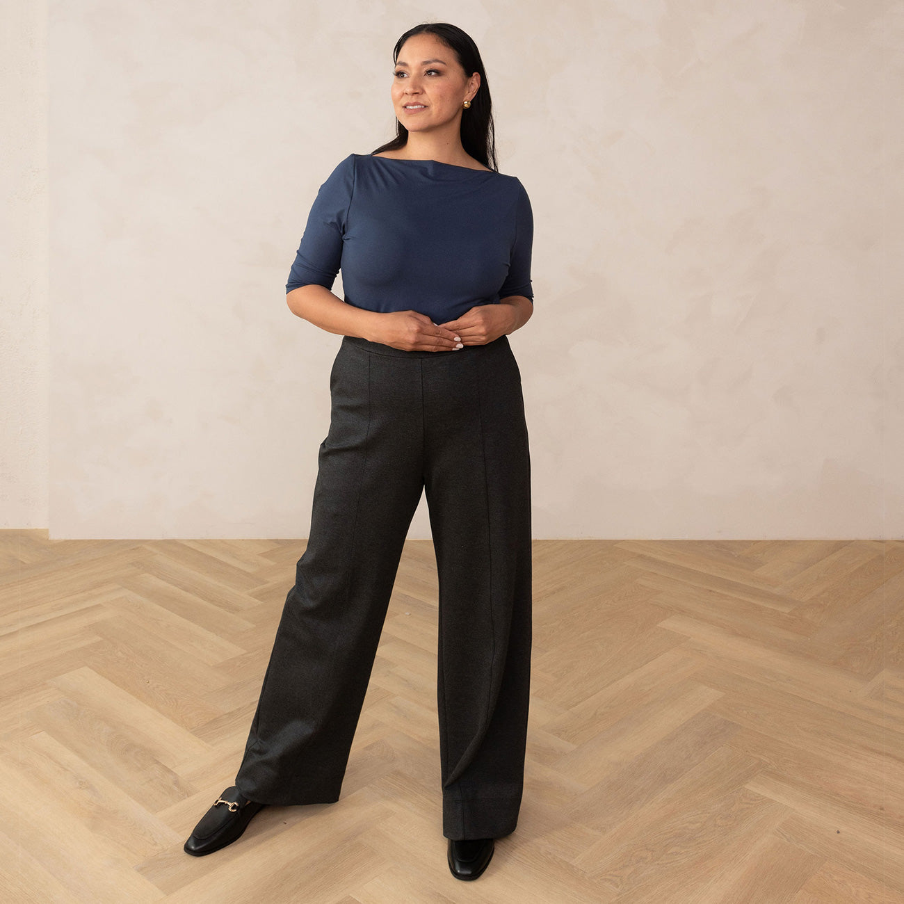 woman wearing a navy blue boat neck top and grey high waisted wide leg trouser pants