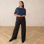 woman wearing a navy blue boat neck top and grey high waisted wide leg trouser pants
