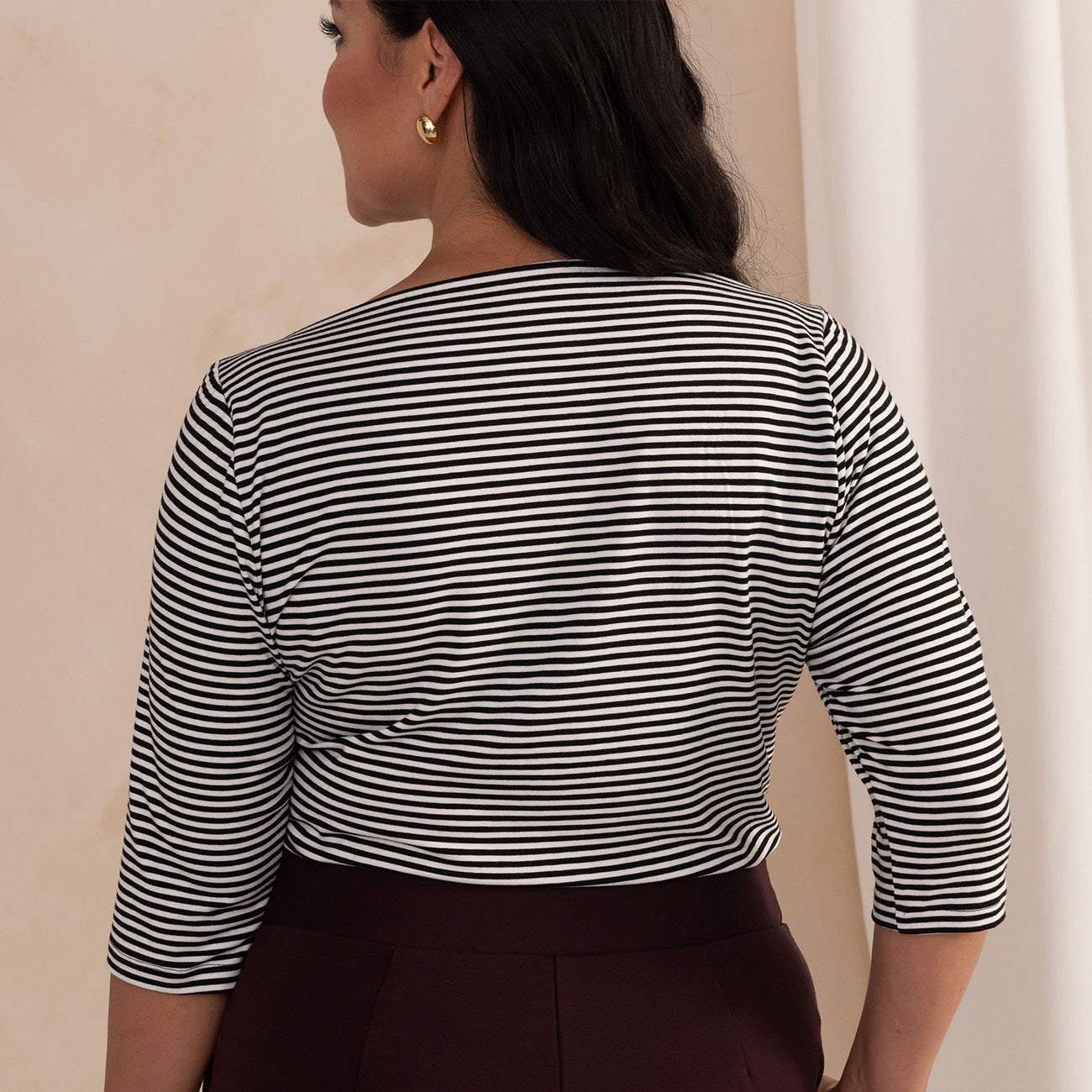 back of a woman wearing a black and white stripes boat neck top 