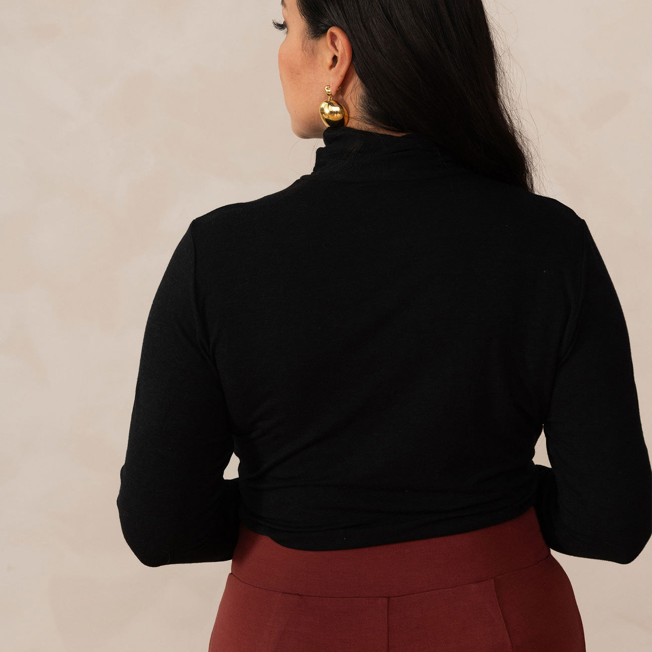 back of a woman wearing a black turtleneck with brick colour pants