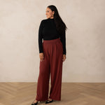 woman wearing a black turtleneck with brick high waisted wide leg pants and black pointy heels 