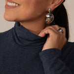 close up image of woman wearing a heathered navy turtleneck and silver earrings