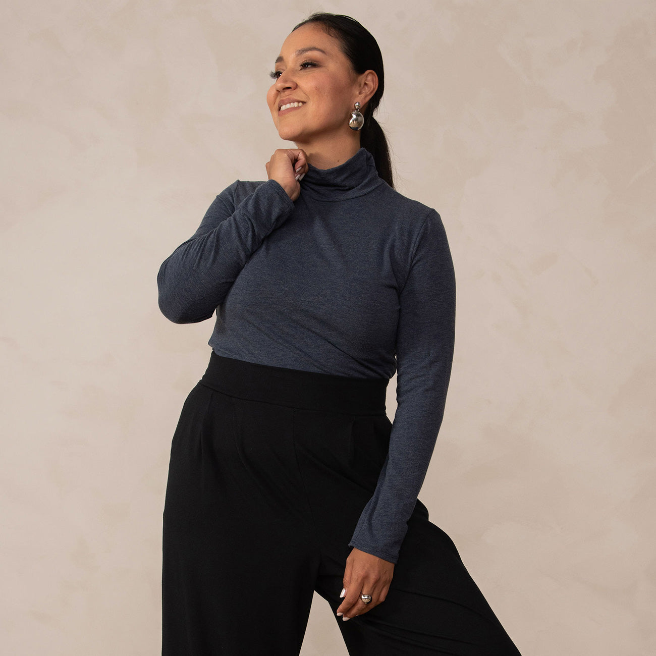 woman wearing a navy turtleneck with black high waisted wide leg pants and black pointy heels 