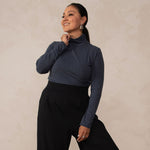 woman wearing a navy turtleneck with black high waisted wide leg pants and black pointy heels 