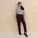 woman wearing light grey turtleneck and aubergine high waisted tailored pants with black loafers