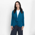 Woman wearing long sleeve blue cardigan with white scoop neckline shirt and grey wide leg pants