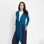 Woman wearing long sleeve blue cardigan with white scoop neckline shirt and grey wide leg pants