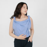 Woman wearing loose periwinkle versatile top with rolled up shoulder sleeves paired with black fitted pants