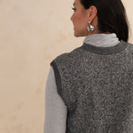 back of a woman wearing a heirloom grey vest and a light grey turtleneck 