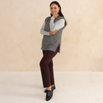 woman wearing a heirloom grey vest paired with a light grey turtleneck and aubergine tailored pants with black loafers